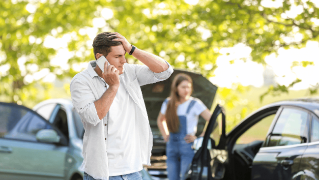 man on phone looking upset after a car accident